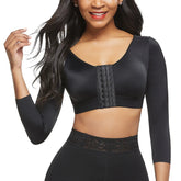 Woman wearing a black long-sleeve sports bra and leggings on a white background